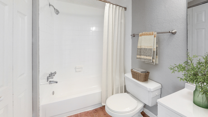 Bathroom, toilet, tub, curved shower rod, and curtain, large mirror