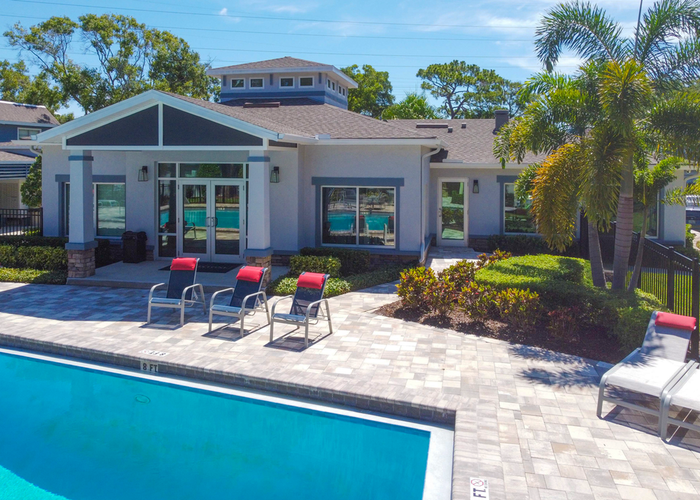 Exterior Of Leasing Office, pool with sundeck, blue chairs and lounge chairs, palm trees