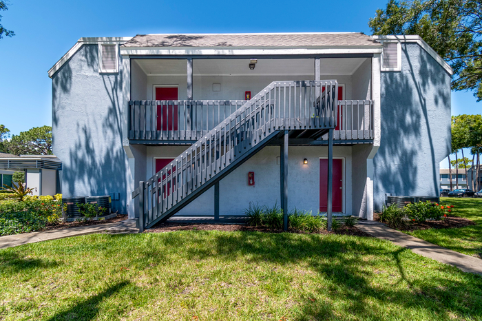 Exterior two story apartment with blue exterior, grass, blue sky