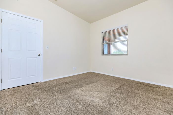 Unfurnished bedroom with carpet, window, and neutral walls at Bella Vista Place Apartments in El Paso