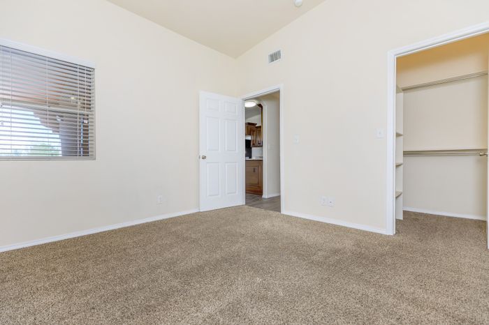 Bedroom with carpet, windows, and doorway leading toward the kitchen at Bella Vista Place Apartments