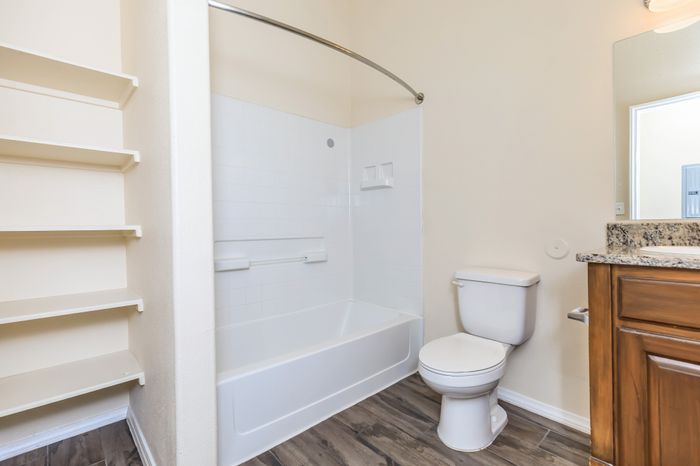 Apartment bathroom with tub and shower combination, toilet, and built-in shelving at Bella Vista Place