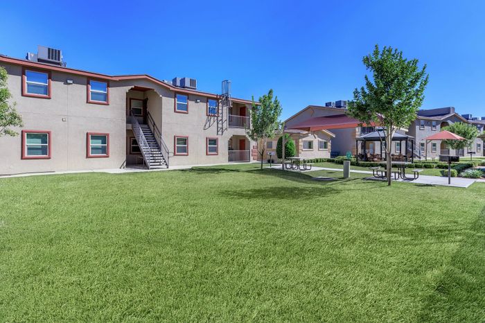 Outdoor courtyard with green lawn and apartment buildings at Bella Vista Place Apartments in El Paso, TX