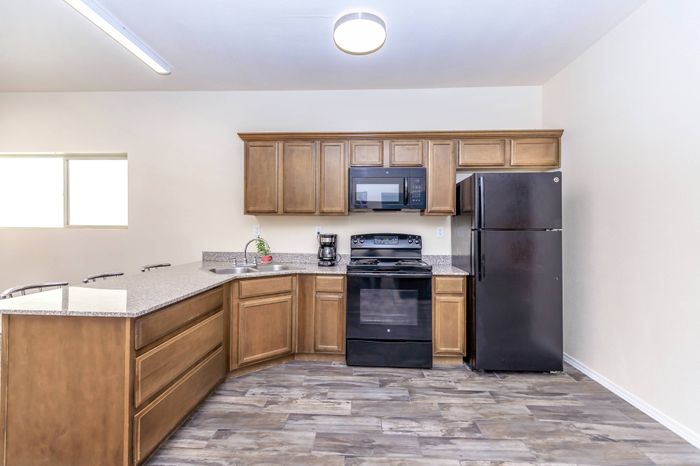 Community room with kitchen, lounge seating, dining tables, and TV at Bella Vista Place Apartments in El Paso