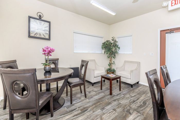 Apartment dining area with table, chairs, windows, and wood-style flooring at Bella Vista Place Apartments