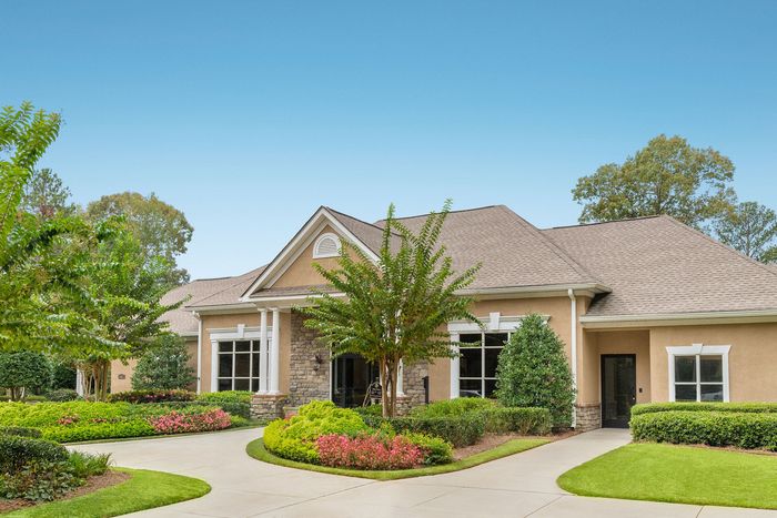 Charming suburban home with elegant stone facade, lush landscaped garden, and inviting walkway.