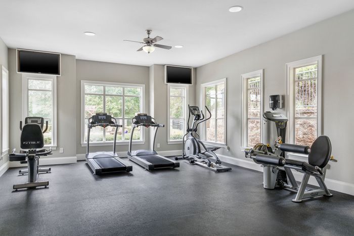 Modern fitness center with large windows, treadmills, exercise bike, and weight machines offering a bright and energizing workout environment.