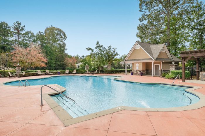 Inviting outdoor swimming pool area surrounded by lush greenery and modern patio furniture, perfect for relaxation and social gatherings.