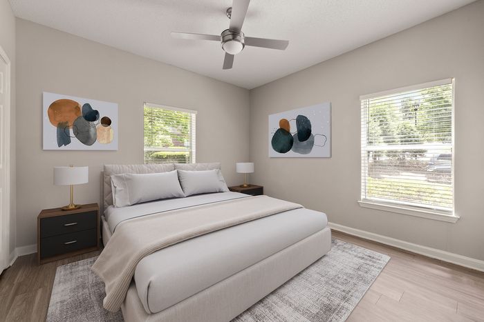 Elegant bedroom with modern art, featuring a plush bed, stylish side tables, and natural light from large windows.