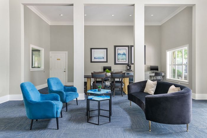 Modern and inviting office lounge with sleek blue chairs, plush black sofa, and a contemporary work area.