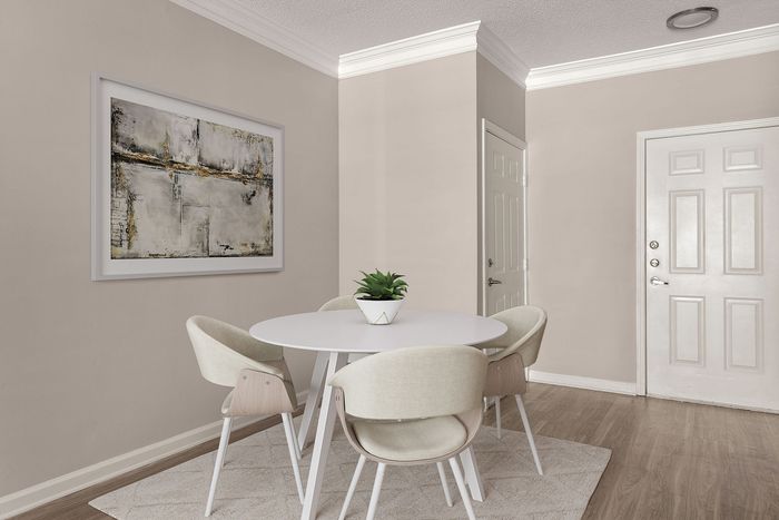 Elegant dining area featuring a modern white round table, chic beige chairs, and contemporary art on beige walls.
