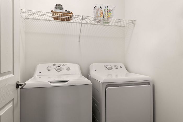 Contemporary laundry room with high-efficiency washer and dryer, featuring sleek shelving for organized storage.