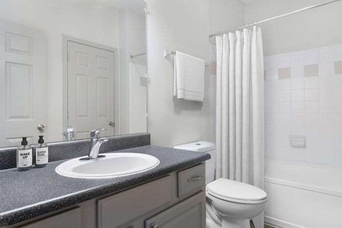 Modern bathroom with sleek countertop, elegant sink, white tiles, and a shower curtain for a fresh, bright look.