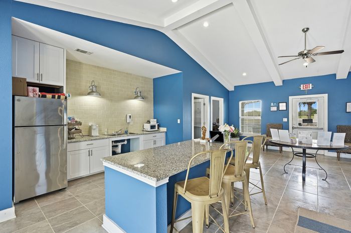 Spacious dining and kitchen area with wooden dining table, bar stools, and modern appliances at Portside Villas in Ingleside, TX