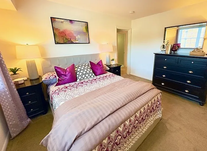 Inviting bedroom with vibrant decor, plush bedding, and modern furnishings bathed in warm natural light.