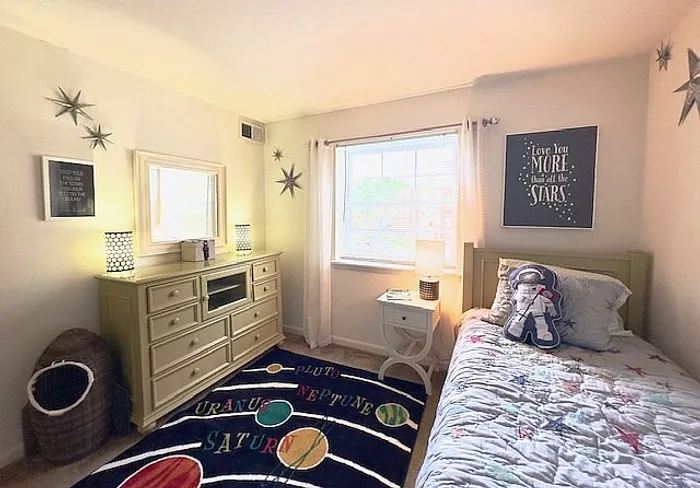 Charming children's bedroom with a space-themed decor, featuring star wall accents, a colorful planetary rug, and cozy bed with plush astronaut.
