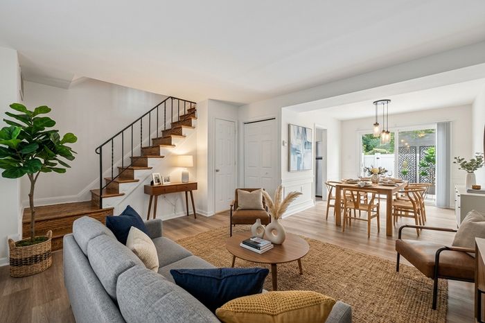Elegant open-concept living and dining area with contemporary decor, stylish staircase, and abundant natural light.