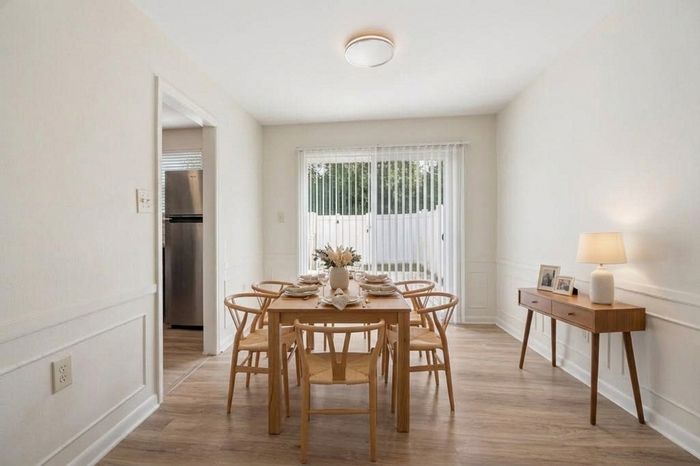Bright dining room with modern wooden furniture, elegant table setting, and natural light from large sliding glass doors.