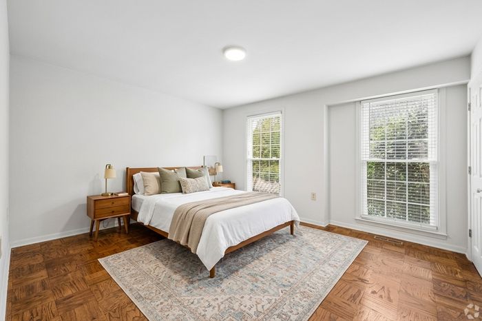 Bright and inviting bedroom with large windows, modern decor, and a cozy bed, offering a serene and comfortable living space.