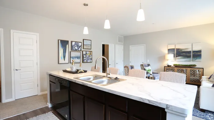 Modern apartment kitchen with sleek marble countertops, stylish pendant lighting, and elegantly framed art on the walls.
