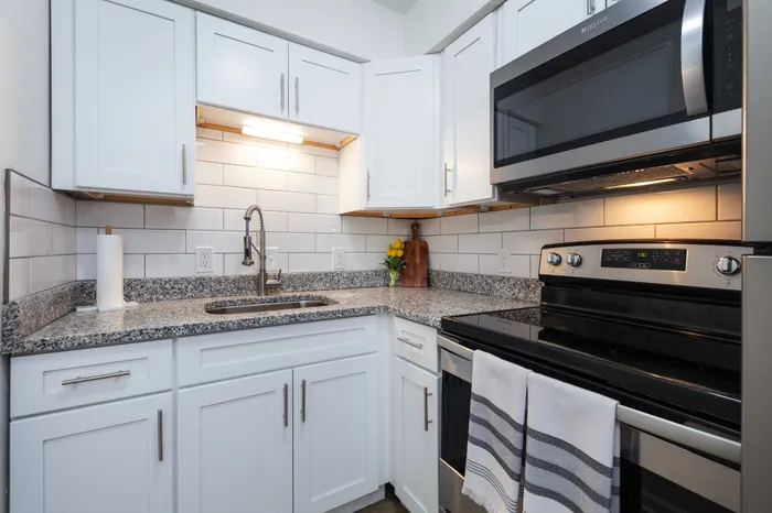 Spacious kitchen with granite countertops, white cabinetry, and stainless steel appliances.
