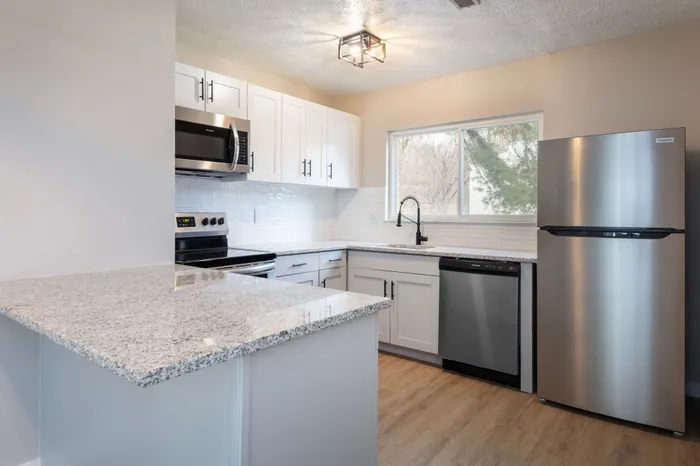 Spacious kitchen with granite countertops, peninsula kitchen islands, Stainless Steel Appliances, window above the sink and overhead lighting.