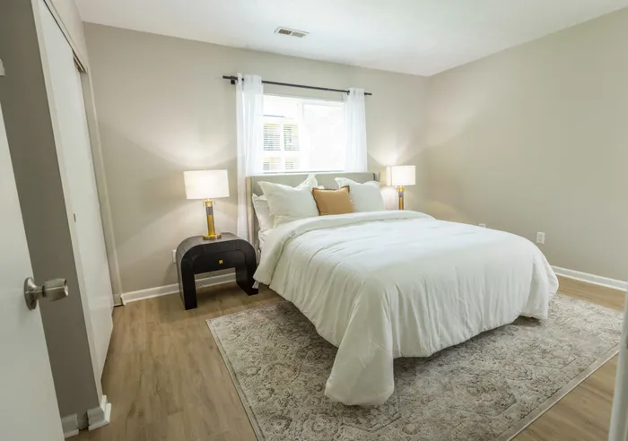 Large master bedroom with window behind the bed, hardwood flooring, and spacious closet space for extra storage.