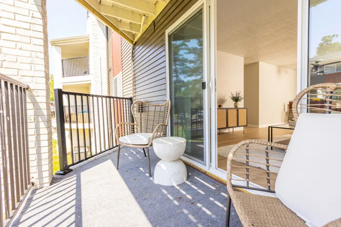 Spacious balcony with large sliding door and patio furniture.