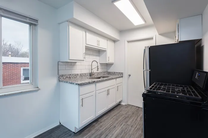 Spacious kitchen with granite countertops, white cabinetry, and stainless steel appliances.