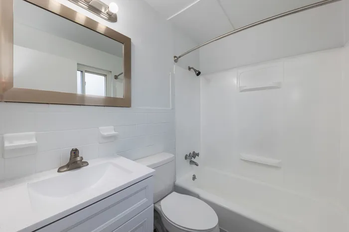 Spacious bathrooms with elevated finishes including a large gold vanity mirror and contemporary lighting, including a large tub.