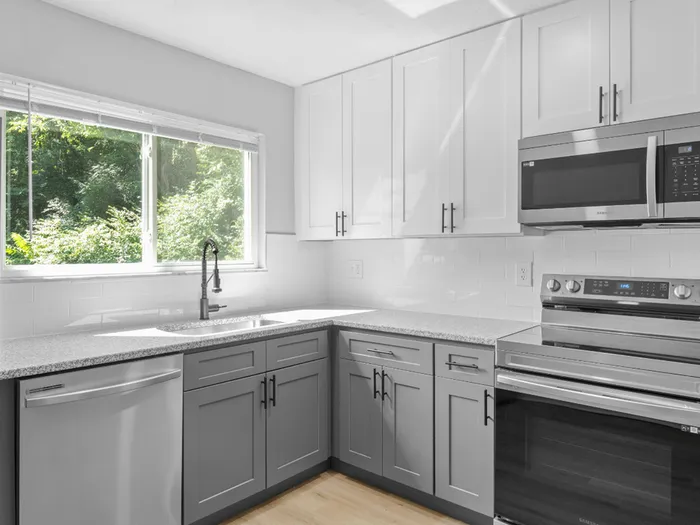 Sleek modern kitchen with stainless steel appliances, white and gray cabinetry, and a large window providing natural light. Explore pet-friendly studio, one-, and two-bedroom apartments in Cincinnati, OH. The Alcove offers upscale living with premium amenities near downtown. apartments for rent in Cincinnati OH, Cincinnati luxury apartments, pet-friendly apartments in Cincinnati, downtown Cincinnati apartments, one bedroom apartments Cincinnati, The Alcove Apartments Cincinnati