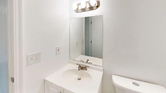 Bright and modern bathroom featuring a sleek vanity with a mirror and contemporary lighting.