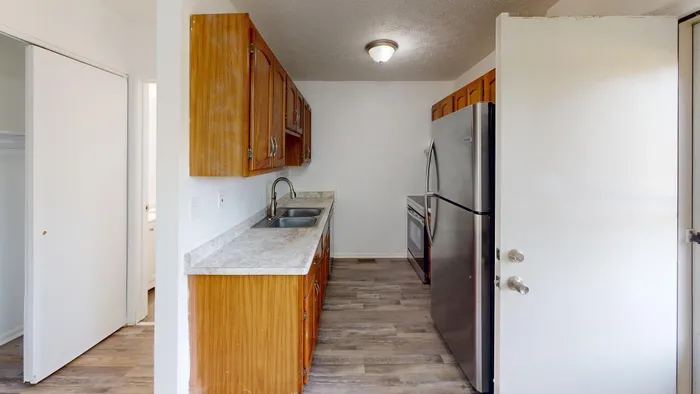 Inviting galley kitchen with wooden cabinets, modern stainless steel appliances, and elegant flooring.
