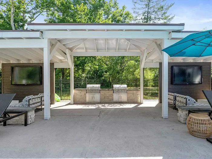 Elegant outdoor lounge area with modern grills and cozy seating under a stylish pergola, perfect for entertaining.