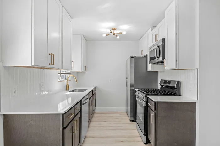 Modern kitchen with sleek cabinetry, stainless steel appliances, elegant gold fixtures, and bright lighting.