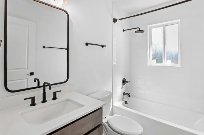 Bright and elegant bathroom with modern fixtures, featuring a sleek vanity, large mirror, and luxurious rainfall shower.