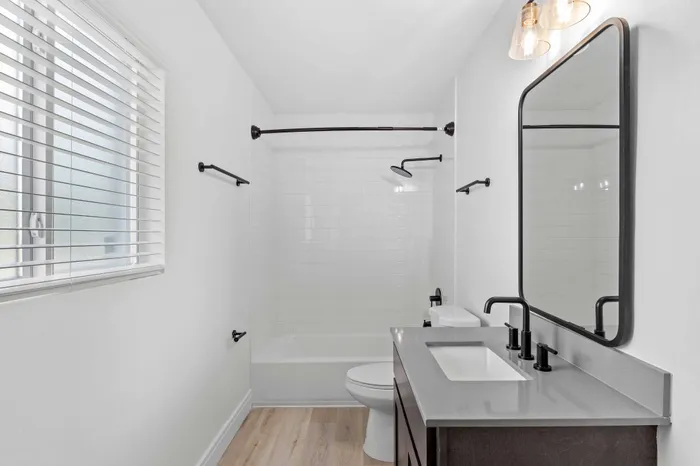 Bright and modern bathroom featuring a chic vanity with a spacious sink, elegant fixtures, and a pristine shower area with sleek tiles.