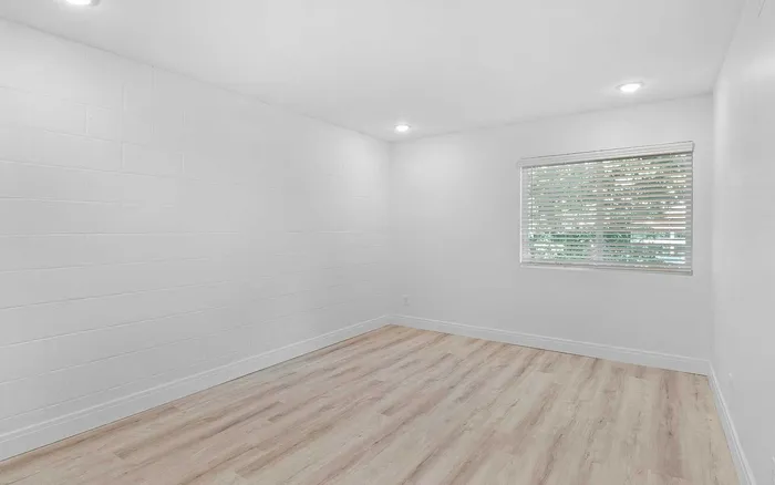 Bright, airy room with elegant wood flooring and large window for natural light.