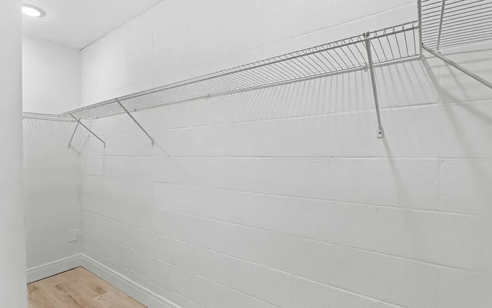 Spacious walk-in closet with sleek wire shelving and bright lighting, perfect for maximizing storage.