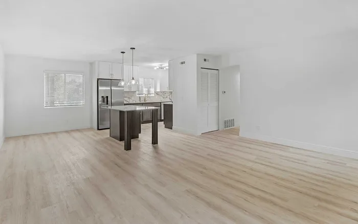 Bright, contemporary open-concept space with wood flooring, modern kitchen island, and sleek stainless steel appliances, ideal for stylish living.