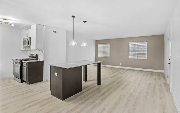 Modern open-plan kitchen and living area with elegant pendant lighting and sleek wood flooring.