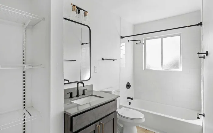 Modern bathroom featuring sleek black fixtures, a spacious vanity, and bright natural lighting from the window.