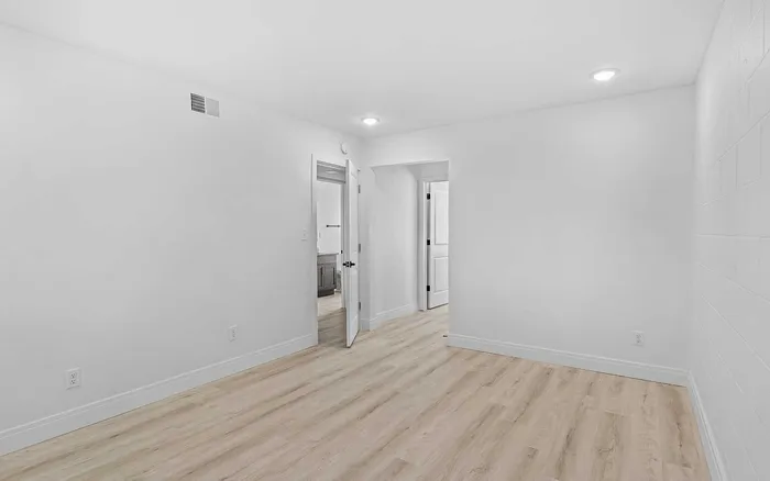 Bright, freshly painted room with sleek wood flooring, recessed lighting, and modern white doors.