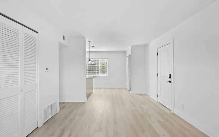 Bright and modern open space featuring light wood flooring, two pendant lights, and large windows with shutters, offering a blank canvas for personalized design.