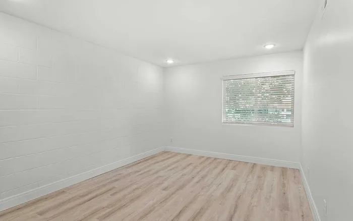 Bright and spacious room with modern wood flooring and large window, offering ample natural light.
