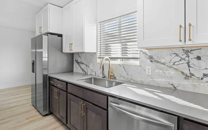 Elegant kitchen with modern stainless steel appliances, marble backsplash, and abundant natural light.