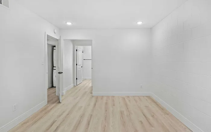 Bright, newly renovated room with modern wood flooring and fresh white walls, offering a sleek and minimalistic design.