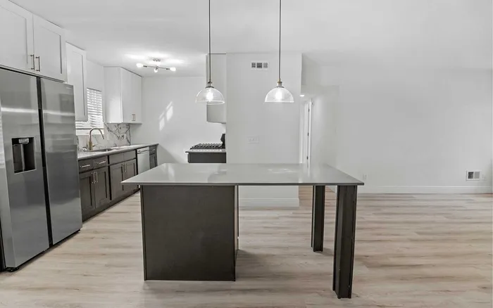 Modern kitchen with sleek stainless steel appliances, elegant marble backsplash, and stylish pendant lighting over a spacious island.