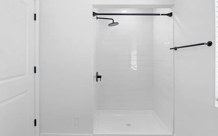 Sleek modern shower with elegant black fixtures and pristine white tiles, offering a luxurious and minimalist bathroom experience.