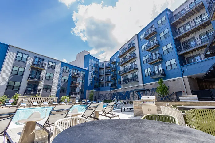 Modern apartment complex with stylish balconies and inviting outdoor pool area set against a clear blue sky.